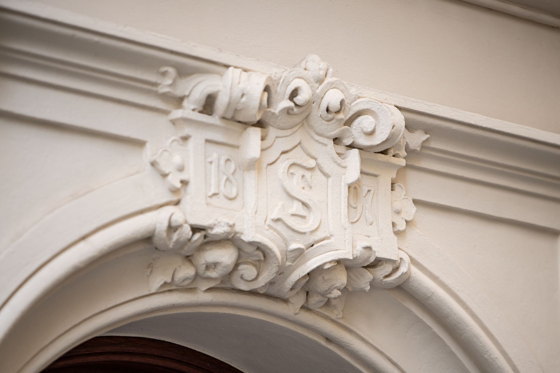 White ornate architectural carving above an arched doorway.