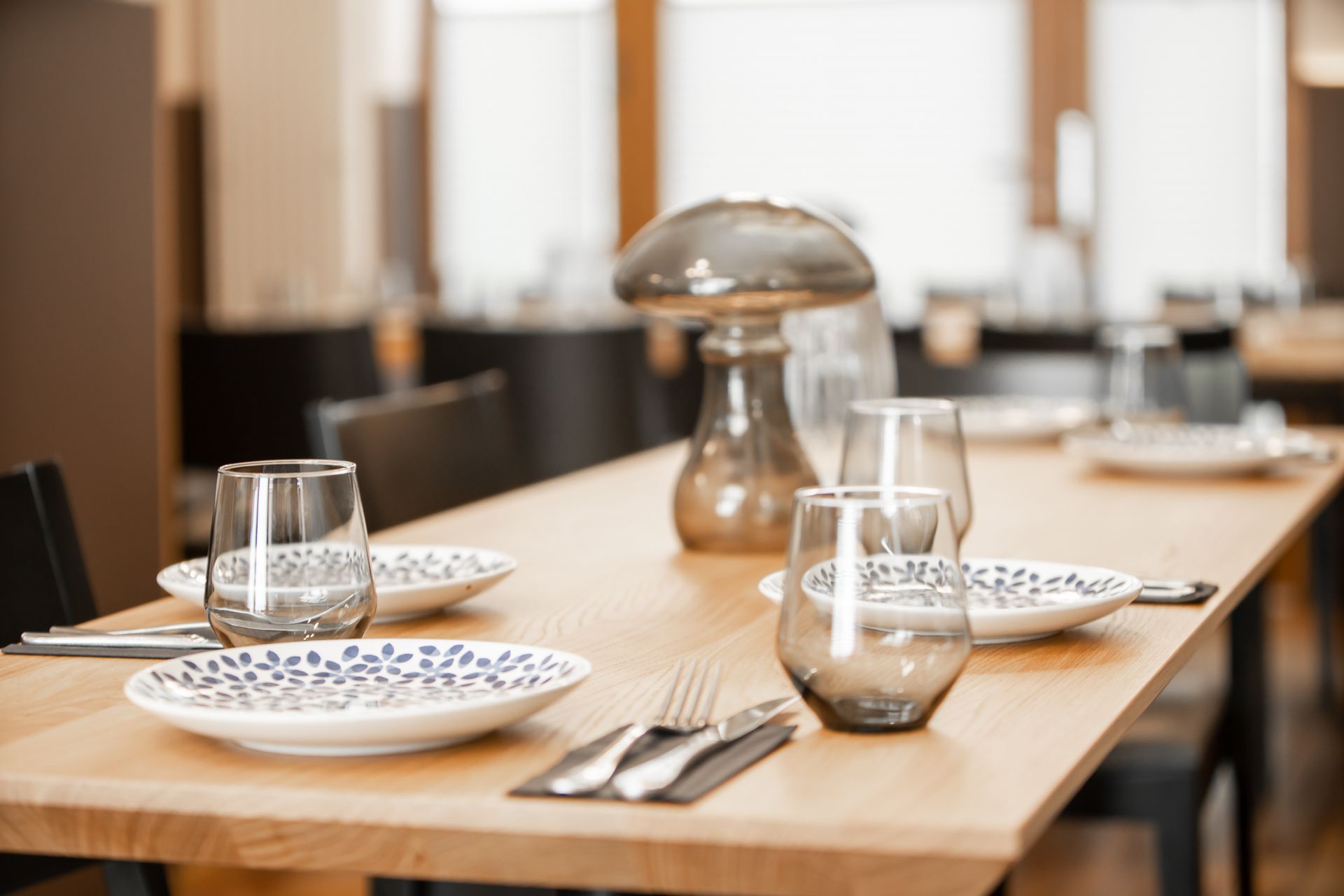 Restaurant table set with plates, glasses, and silverware, featuring a mushroom-shaped centerpiece.