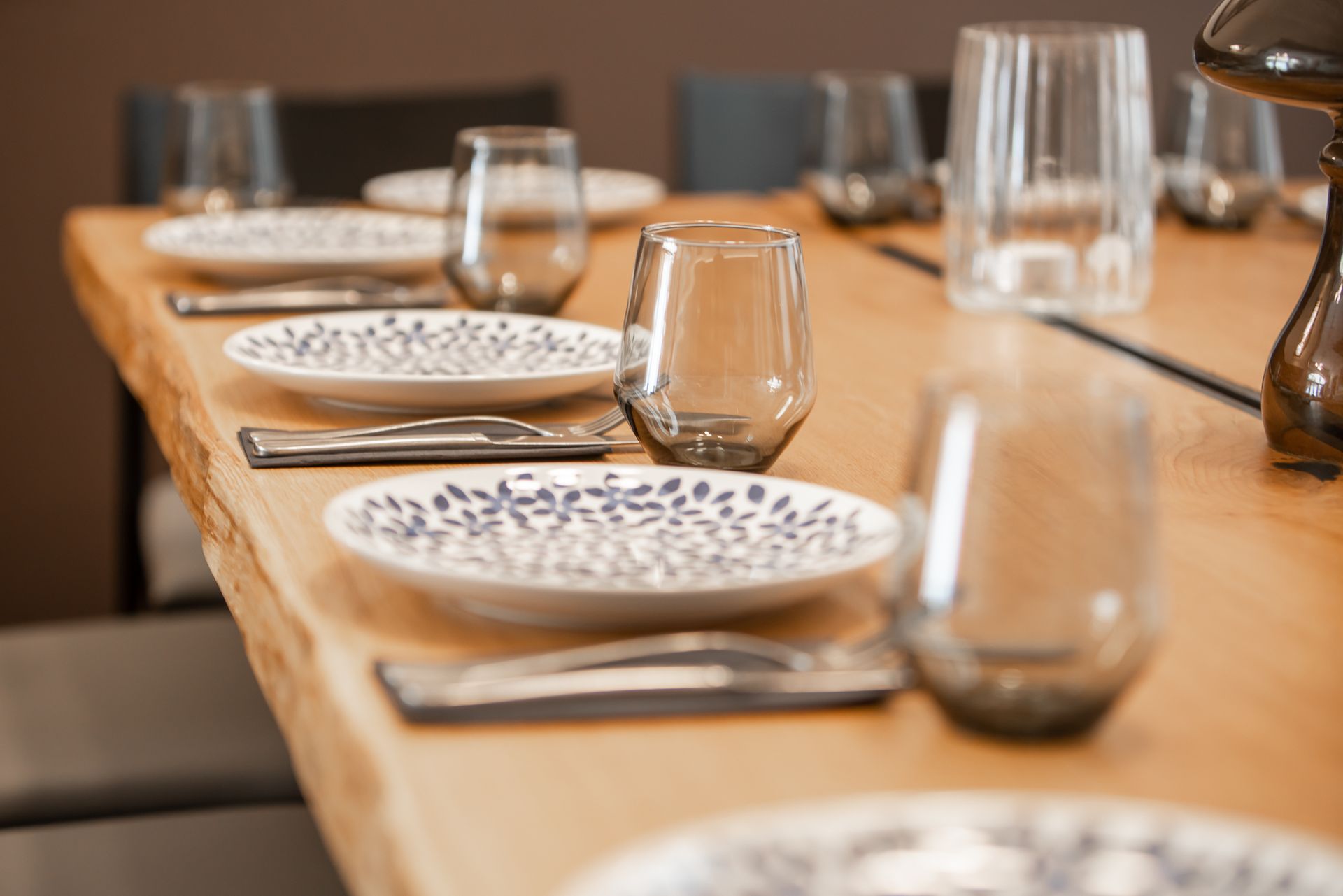 Dining table set with plates, glasses, and cutlery, ready for a meal.