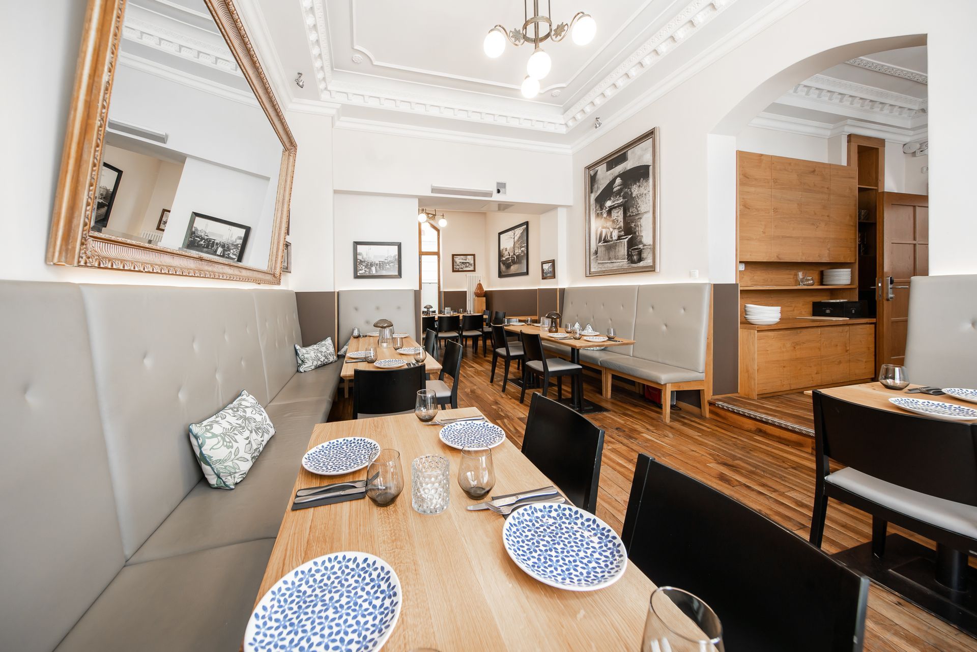 Restaurant interior: tables set with blue patterned plates, gray booths, wooden floors, and vintage decor.