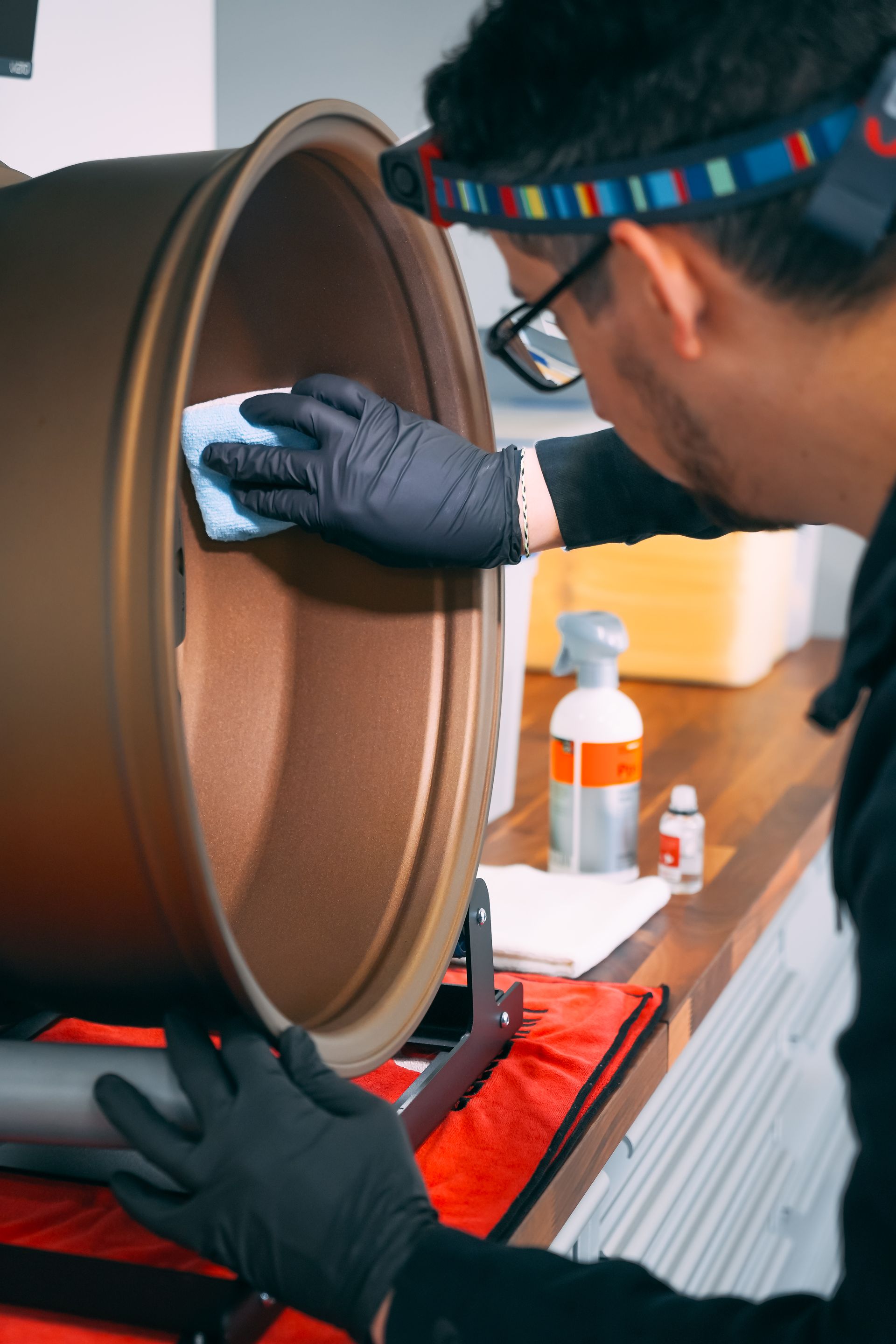 A man wearing a headband is cleaning a wheel with a cloth