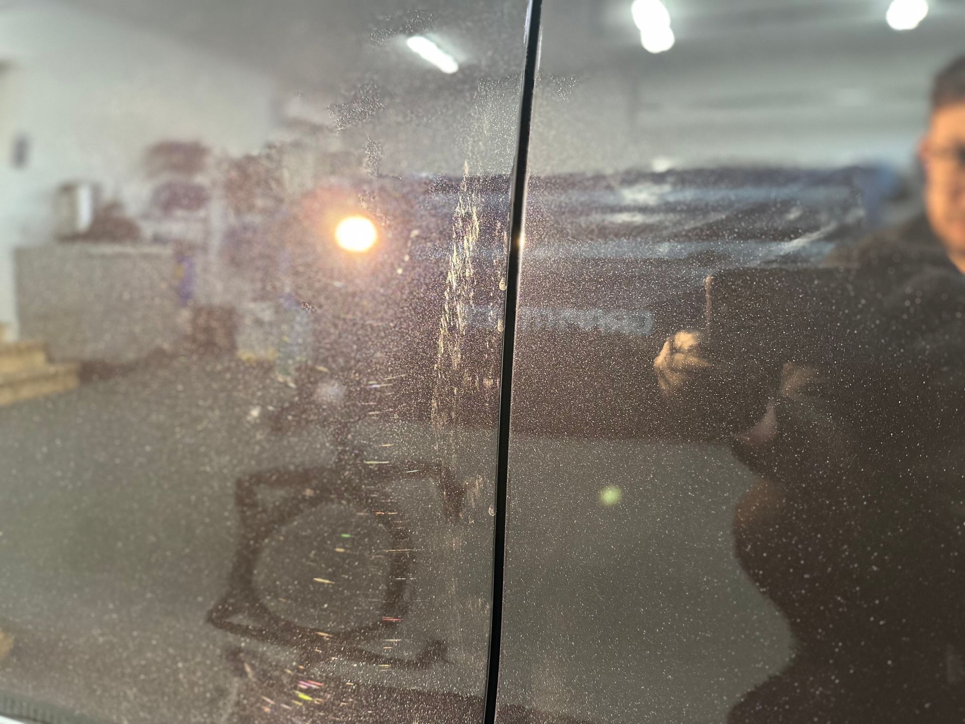 A man is taking a picture of his reflection in a car window.