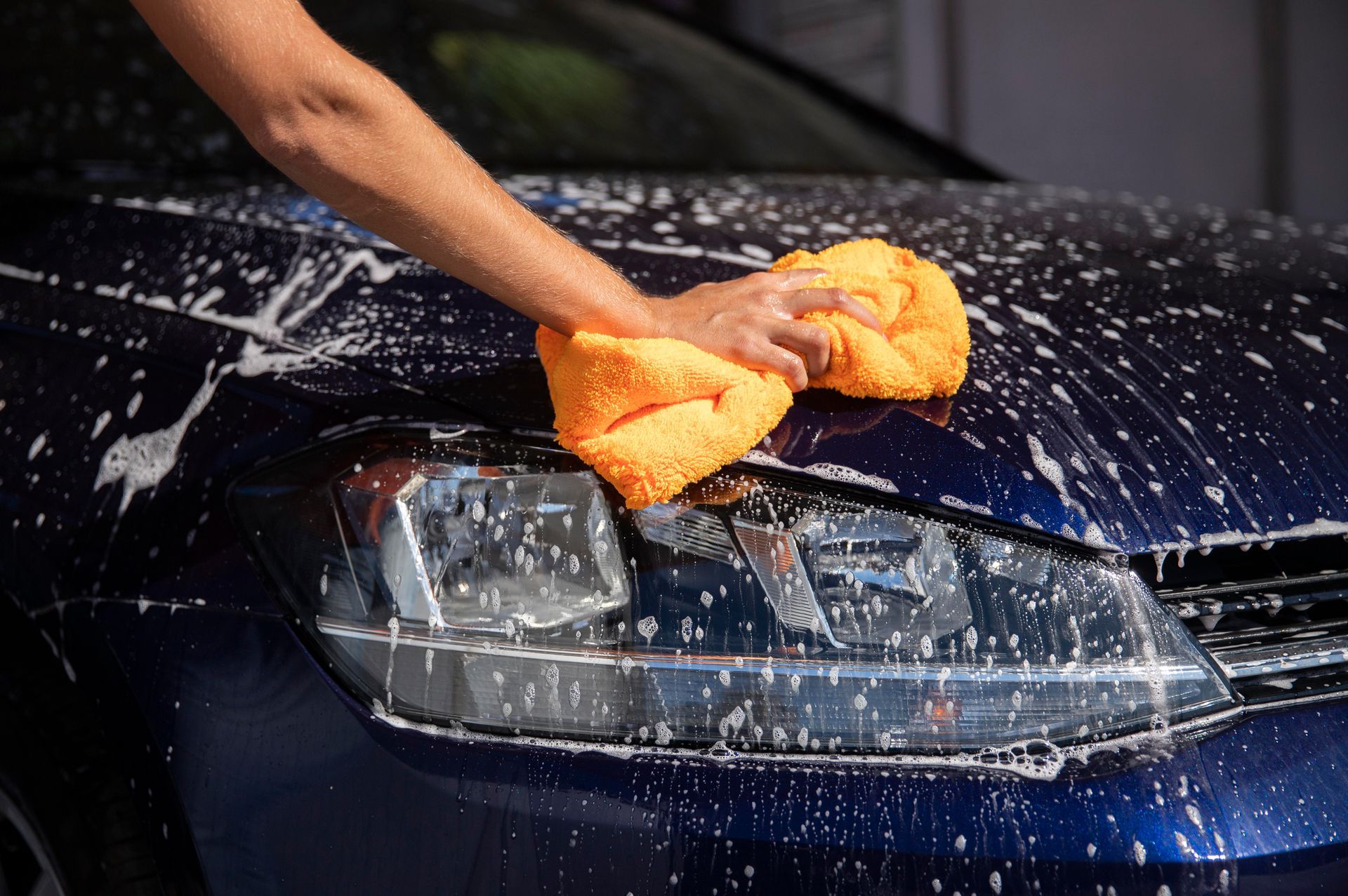 A person is washing a car with a towel.
