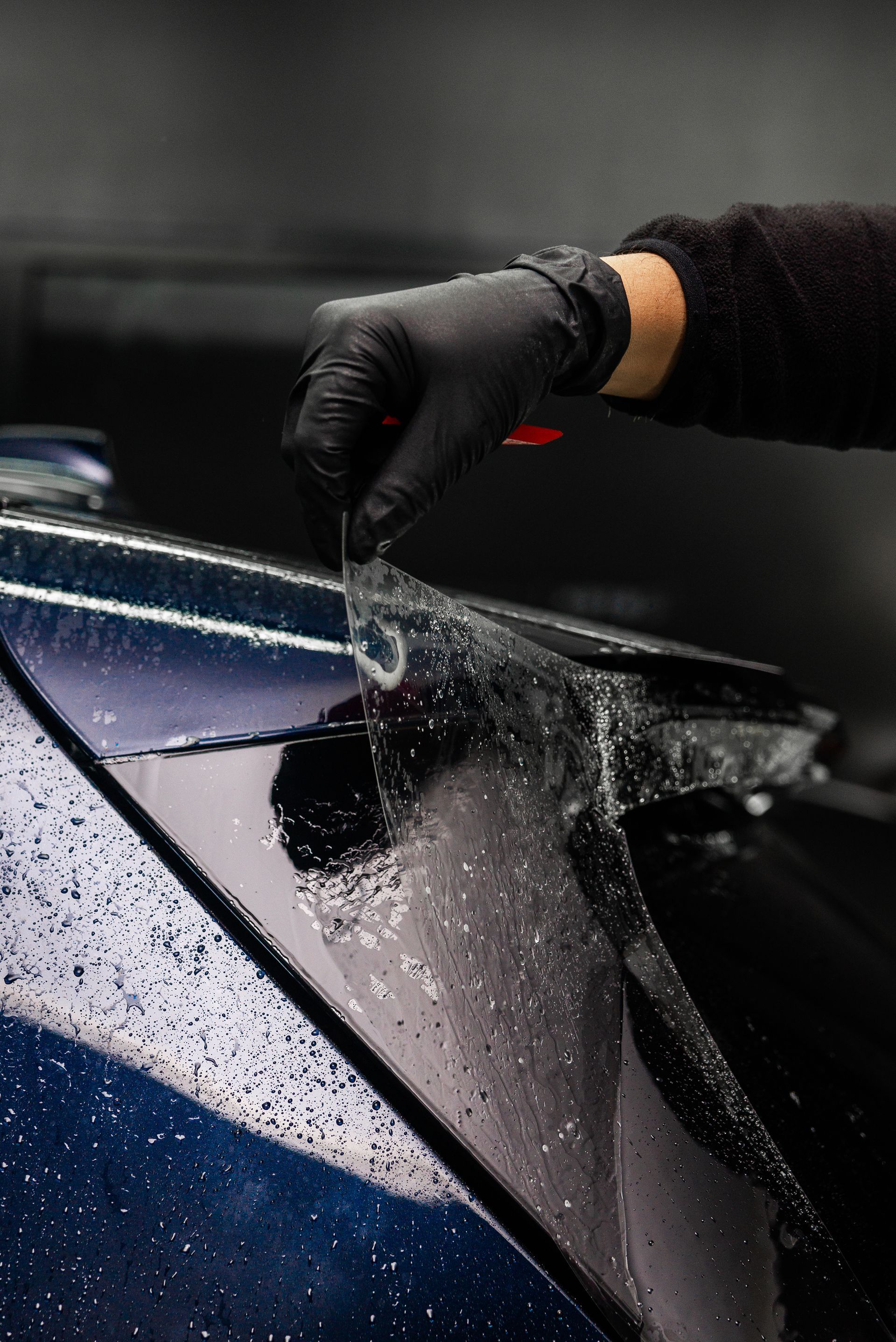 A person is applying a protective film to the windshield of a car.