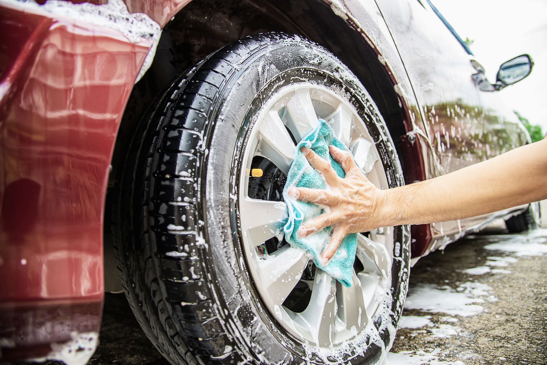 A person is washing a car with soap and a cloth.