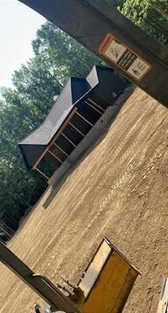 A house with dark roof is built on a graded dirt hill; viewed from the perspective of a construction vehicle.