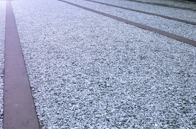 Gravel path with long, dark gray strips running across it.