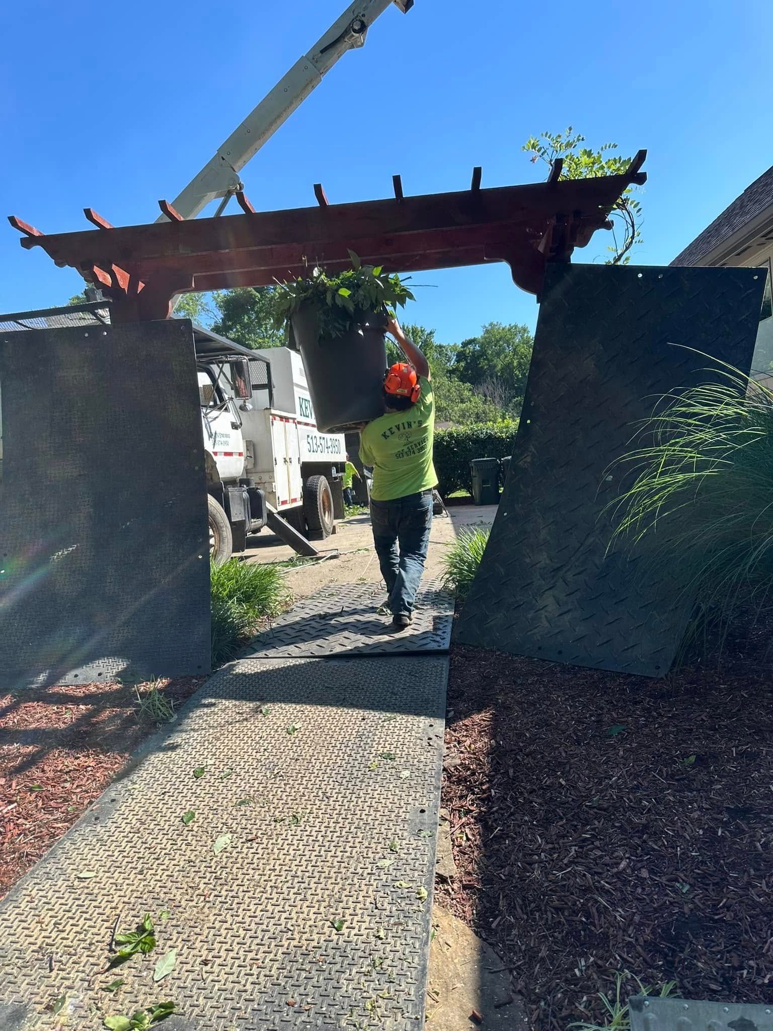 Worker in neon vest beneath a concrete gate being lifted by a crane on a construction site