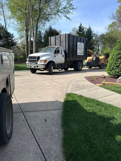 White truck with black trailer on a curved driveway in a sunny residential yard