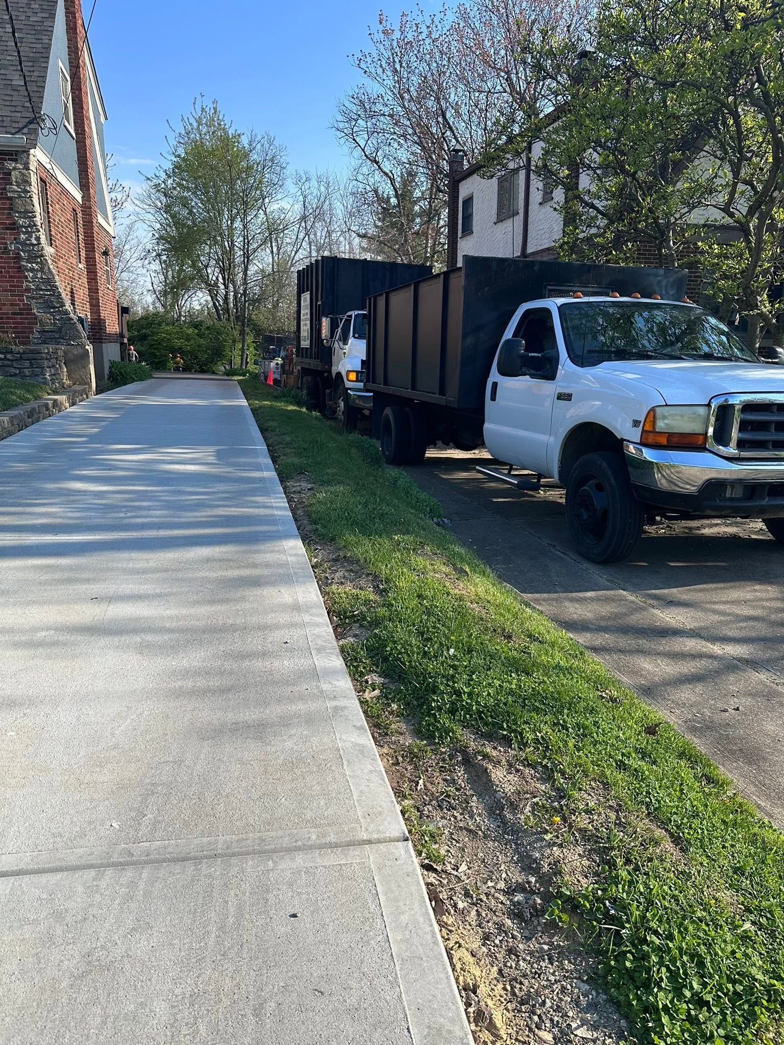 Sidewalk beside a brick building and parked white utility truck on a sunny day
