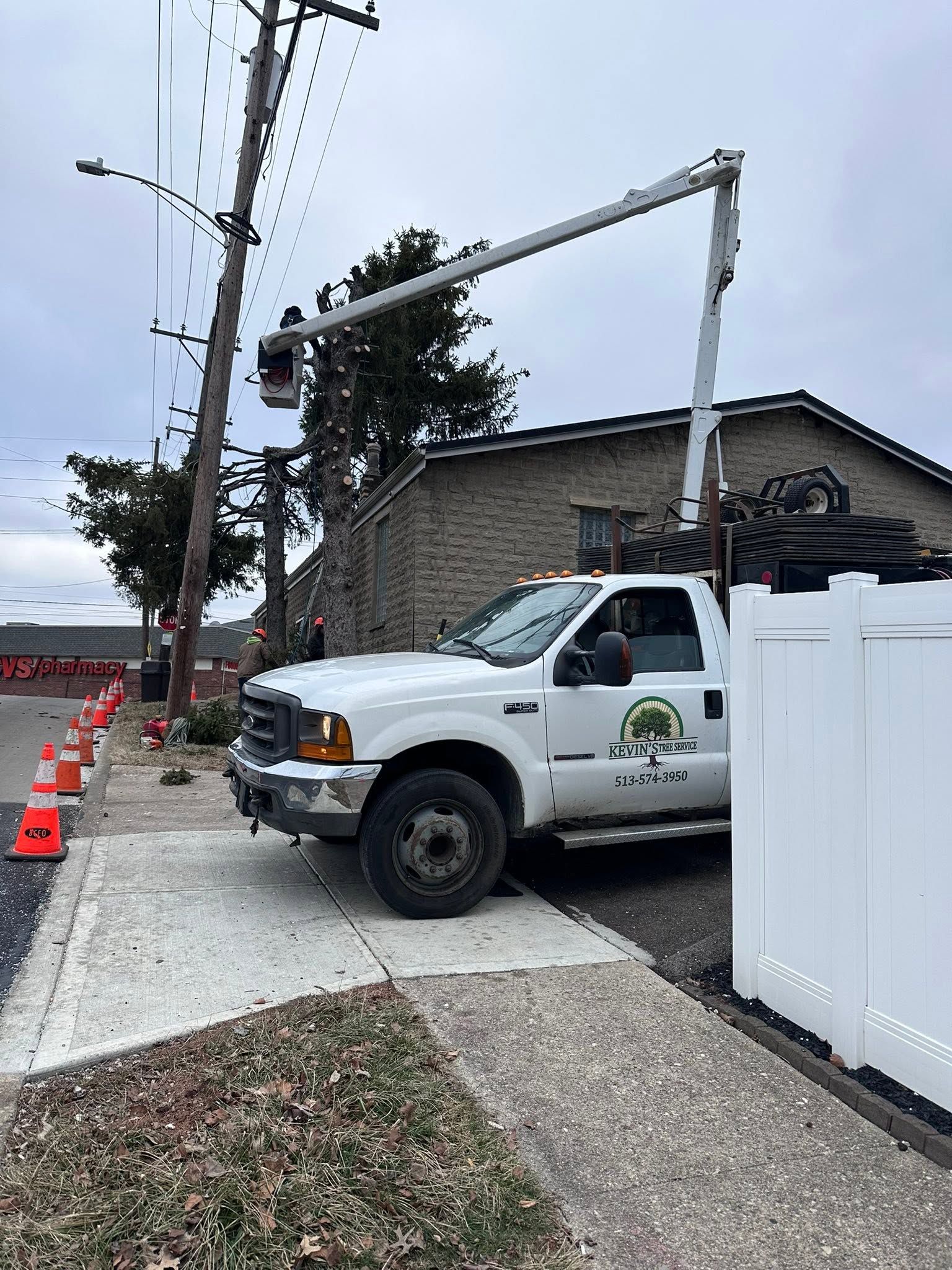 Utility truck beside a damaged utility pole with cones and barricades in a residential yard