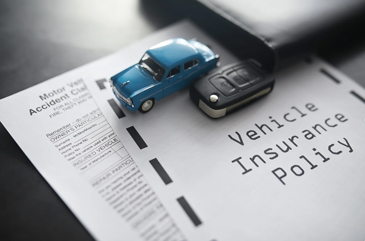 Vehicle insurance policy document with a toy car and car key.