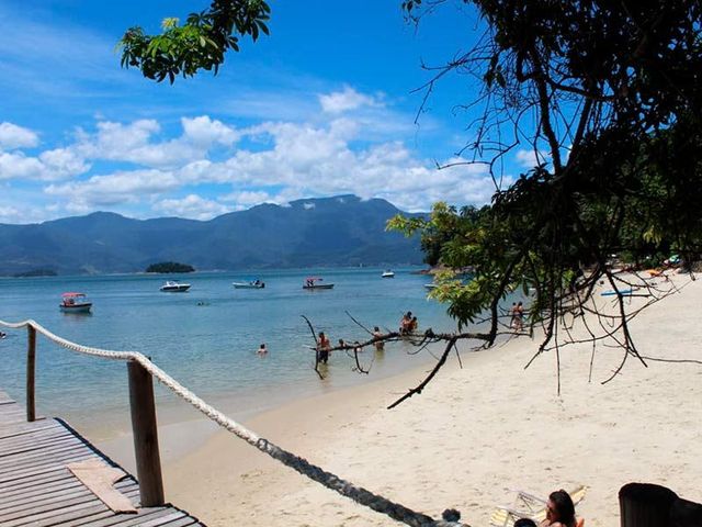 Uma praia com pessoas nadando na água e montanhas ao fundo-pousada-itacuruca-inn