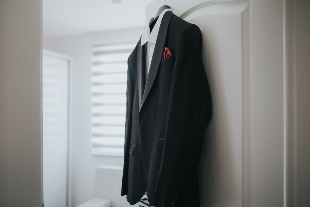 Black suit jacket hanging on a white door in a softly lit room