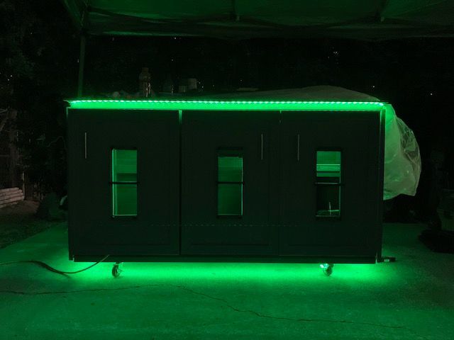 A dark, three-door cabinet illuminated by vibrant green LED strips along the top edge and base.