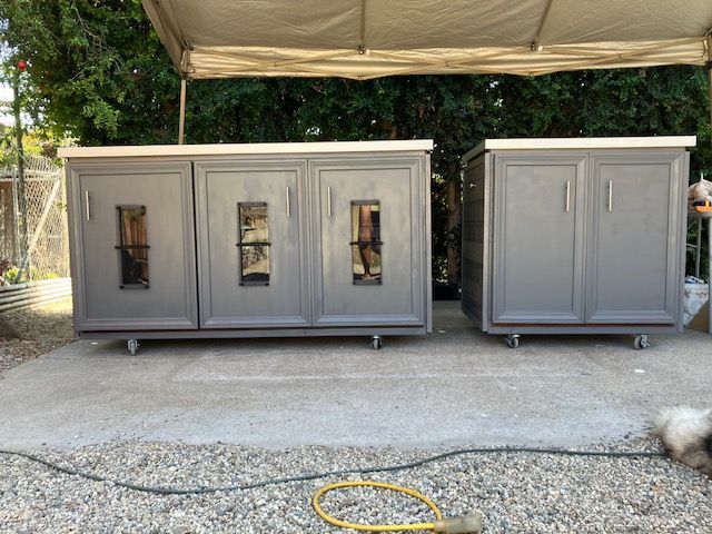 Two grey, mobile cabinets with silver handles stand on a concrete patio under a canopy in an outdoor setting.