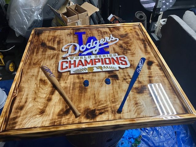 A wooden board featuring a Los Angeles Dodgers World Series Champions sign, two miniature bats, and blue circular markers.