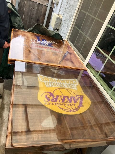 Two wooden tables with glossy epoxy finishes, featuring Los Angeles Lakers and Dodgers championship logos.