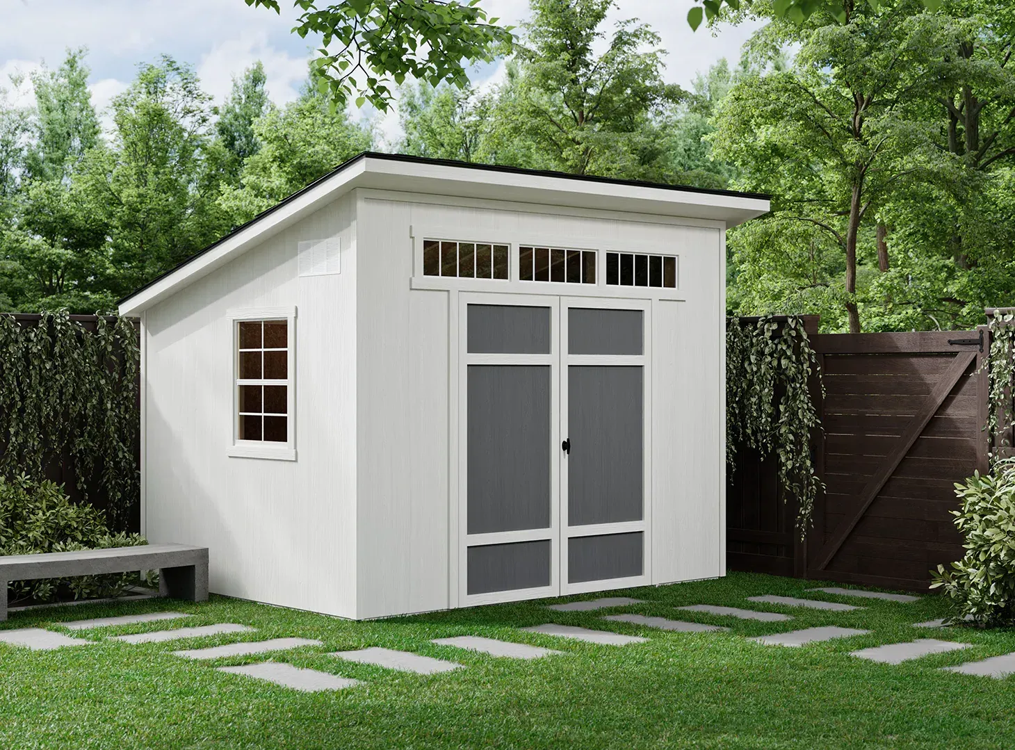 A white modern shed with a slanted roof, double doors, and windows, situated in a green backyard.