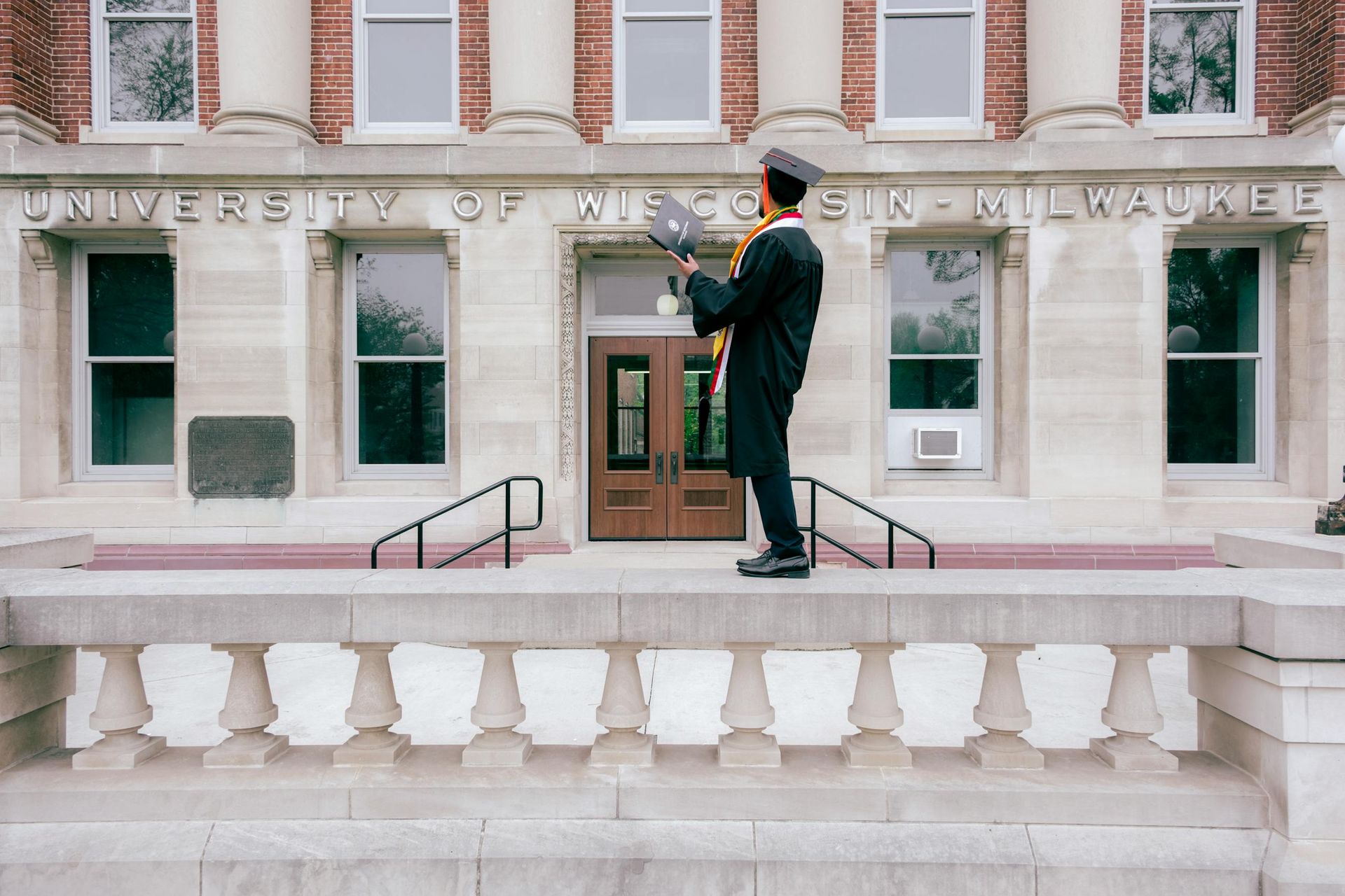 Person on a balcony playing trumpet outside the University of New Orleans building