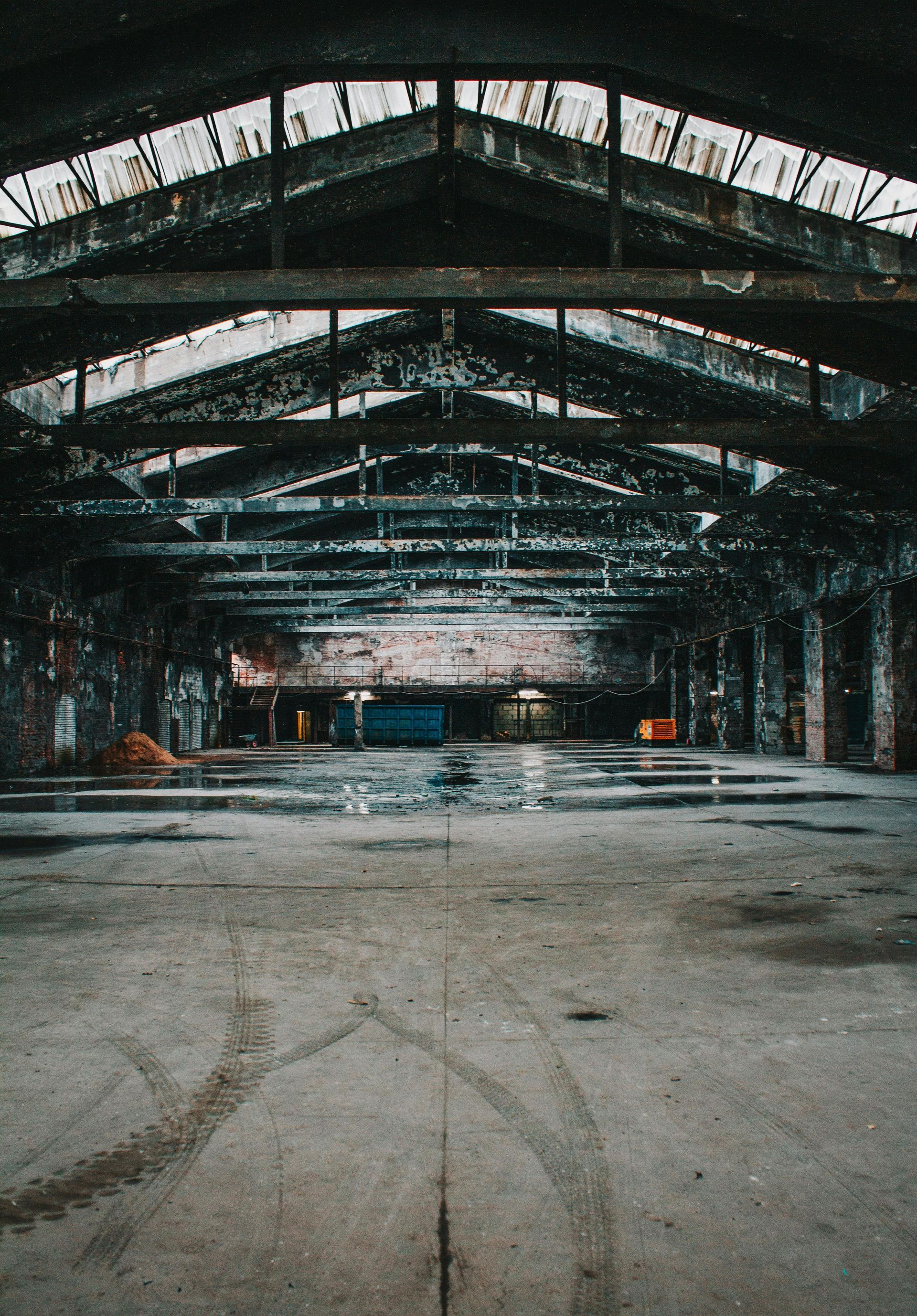 Abandoned warehouse interior with a high metal roof and empty concrete floor