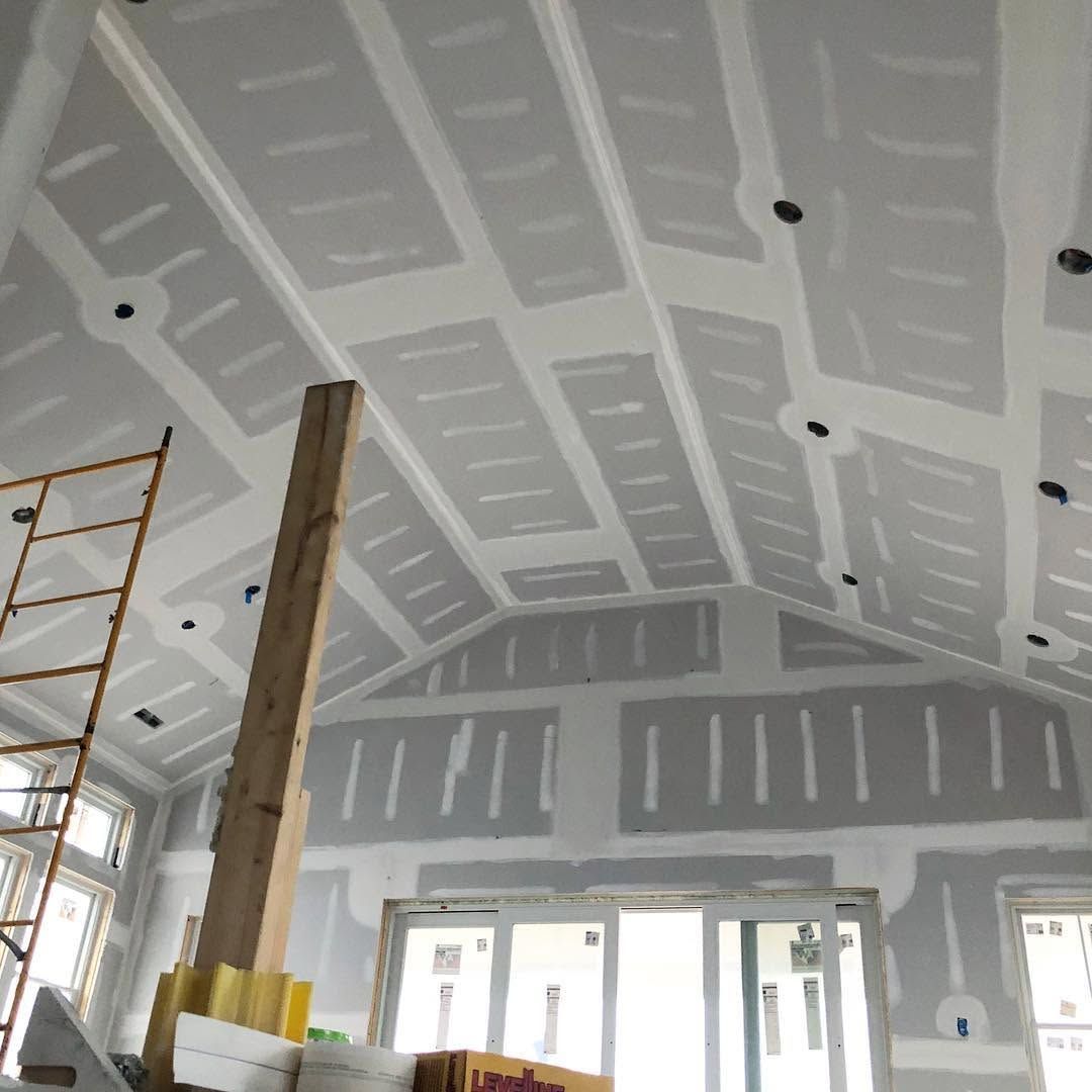Interior under renovation with unfinished drywall ceiling, scaffolding, and exposed wooden support beam.