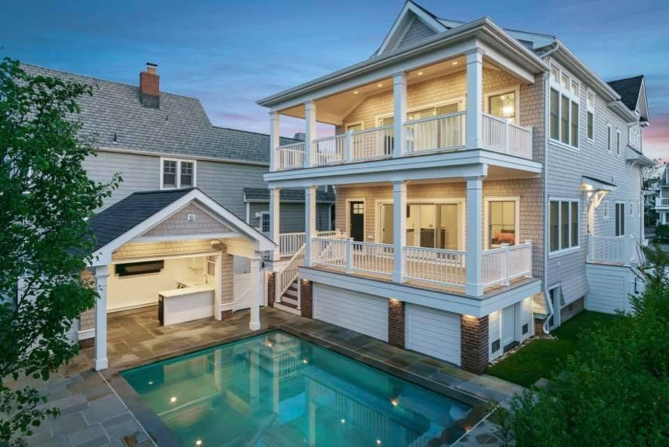 Luxury house with a backyard pool and detached garage at dusk