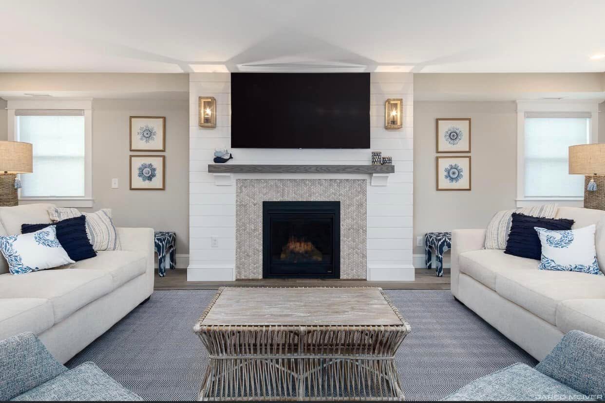 Bright symmetrical living room with two white sofas, central fireplace, and wall-mounted TV.