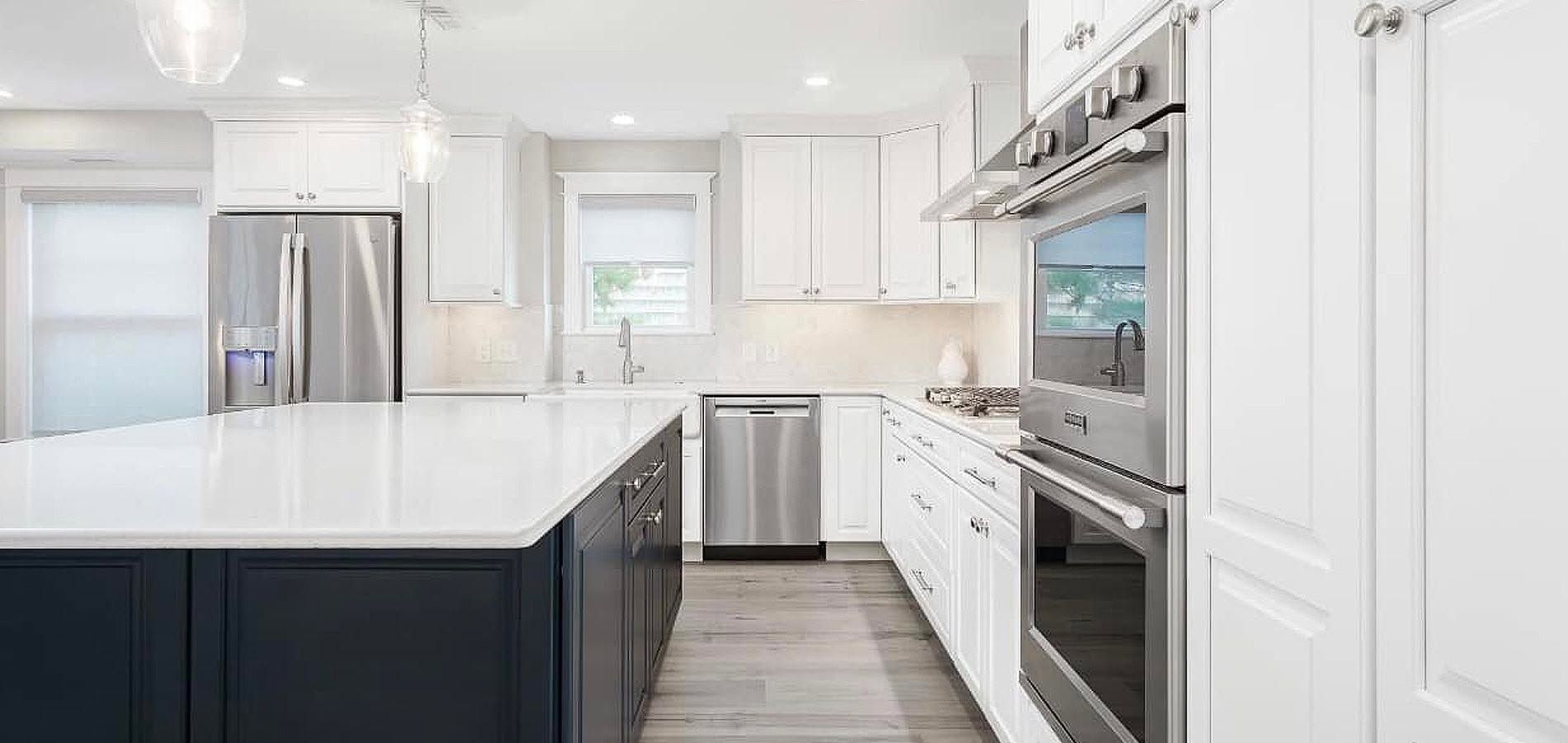 Bright white modern kitchen with stainless steel appliances, island, and gray flooring