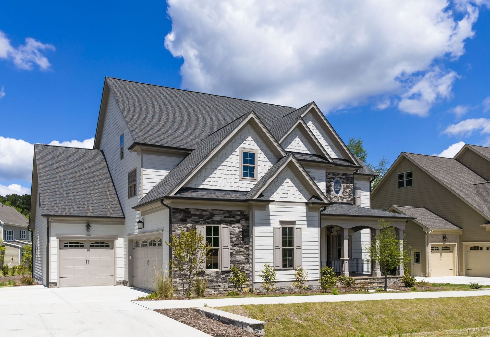 Modern two-story gray house with attached garage and white trim under a blue sky