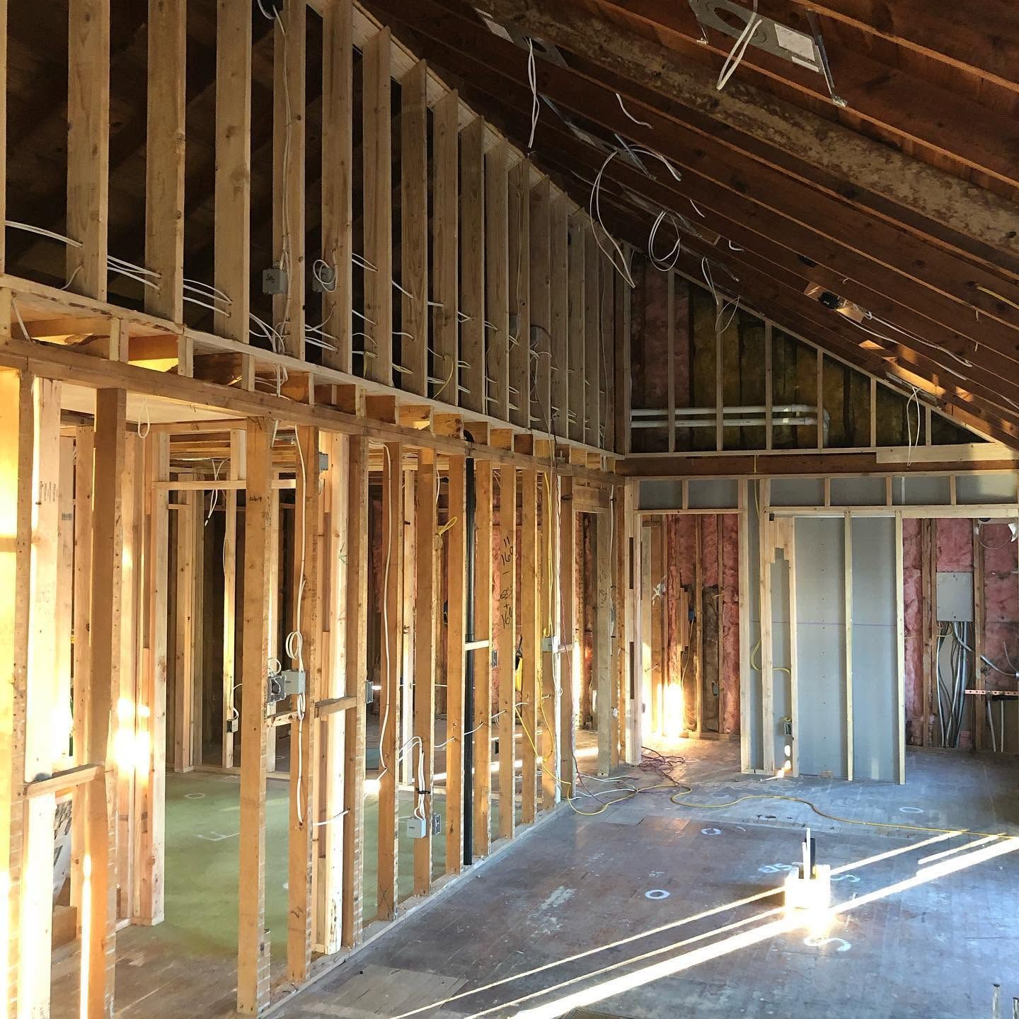 Unfinished attic interior with exposed wood framing, sloped roof, and sunlight on the floor