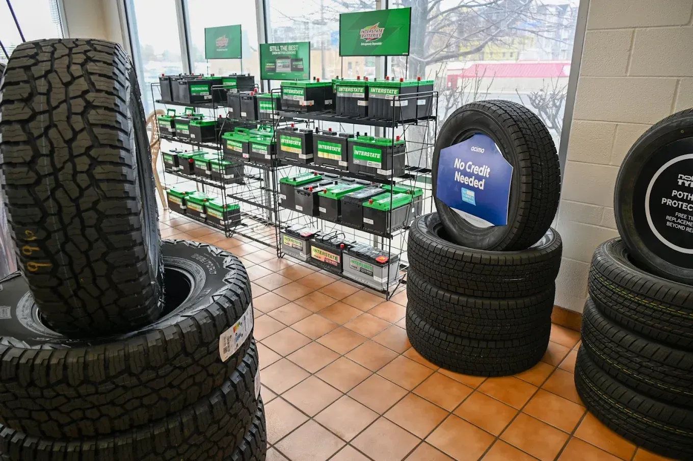 Tire shop display with stacked black tires and green boxed products on metal shelves | Jones Complete Car Care