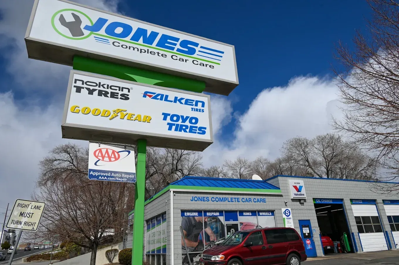 Jones Auto Care sign outside a tire and auto service shop with a red SUV parked nearby | Jones Complete Car Care