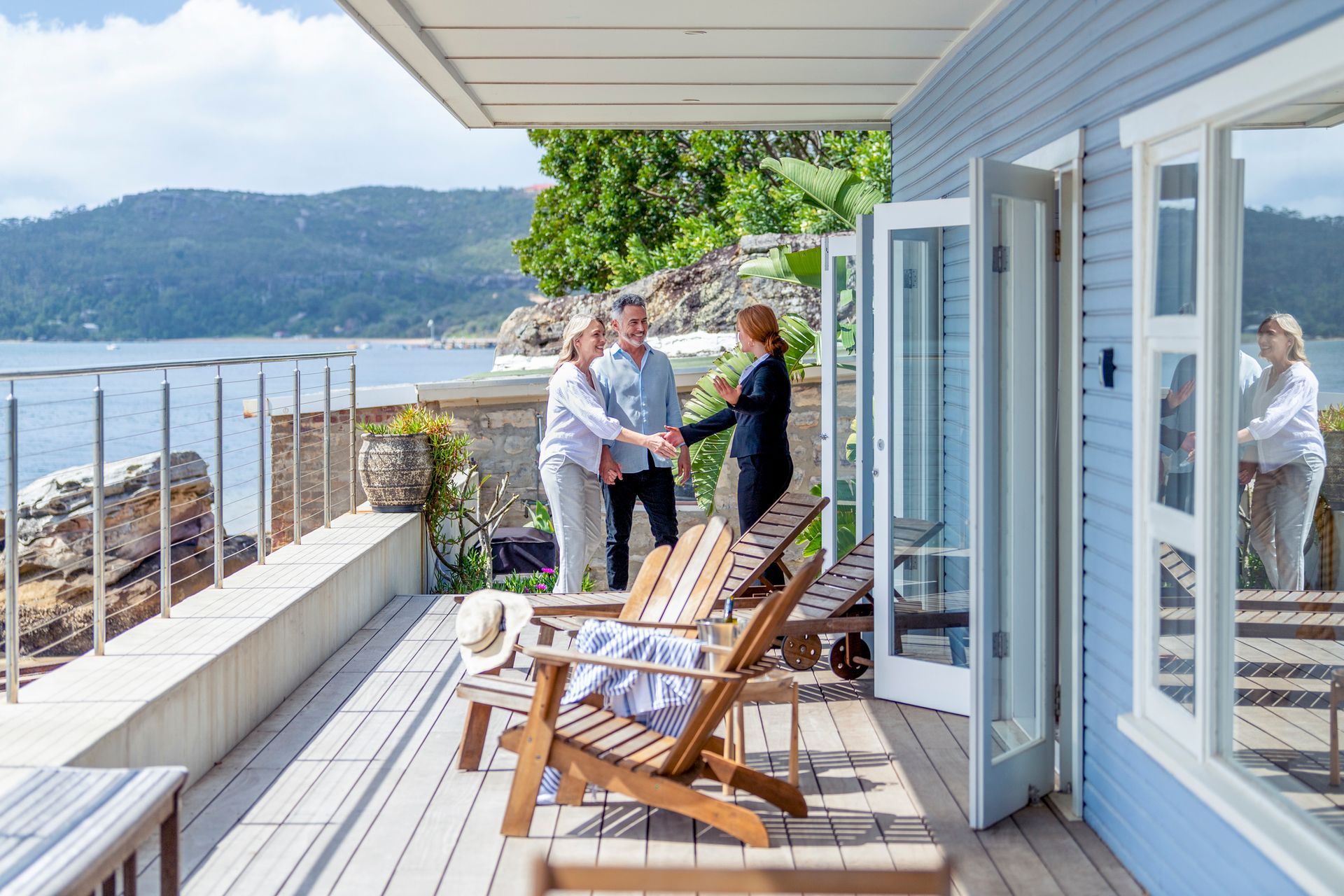 A man and a woman are shaking hands on a deck overlooking the ocean.