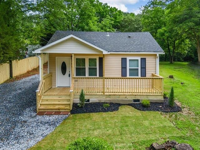 A small house with a porch and a fence in front of it