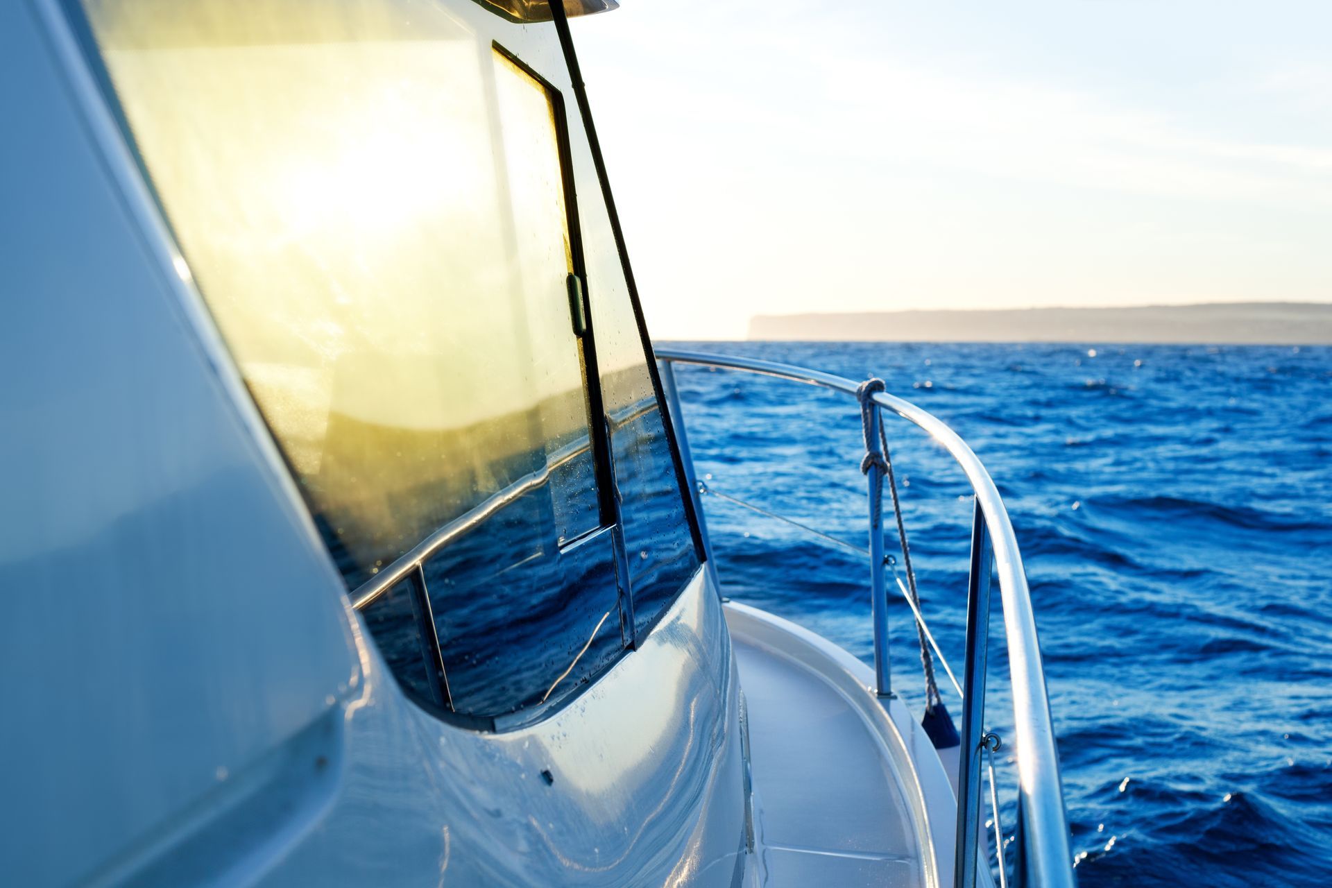 Boat sailing on blue water with sunny reflections on a window.