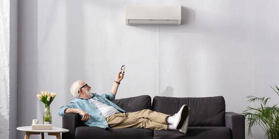 Senior Man Turning On the Air Conditioner — Vashon, WA — Vashon Heating & Cooling Senior Man Turning On the Air Conditioner — Vashon, WA — Vashon Heating & Cooling