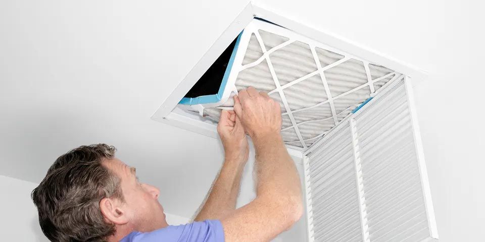 Man Removing Dirty Air Filter — Vashon, WA — Vashon Heating & Cooling Man Removing Dirty Air Filter — Vashon, WA — Vashon Heating & Cooling