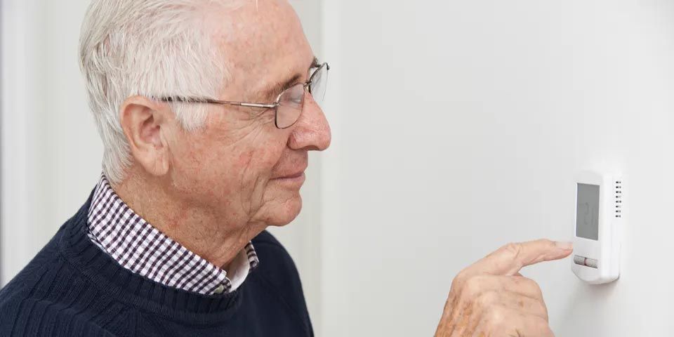 Senior Man Adjusting Central Heating Thermostat — Vashon, WA — Vashon Heating & Cooling