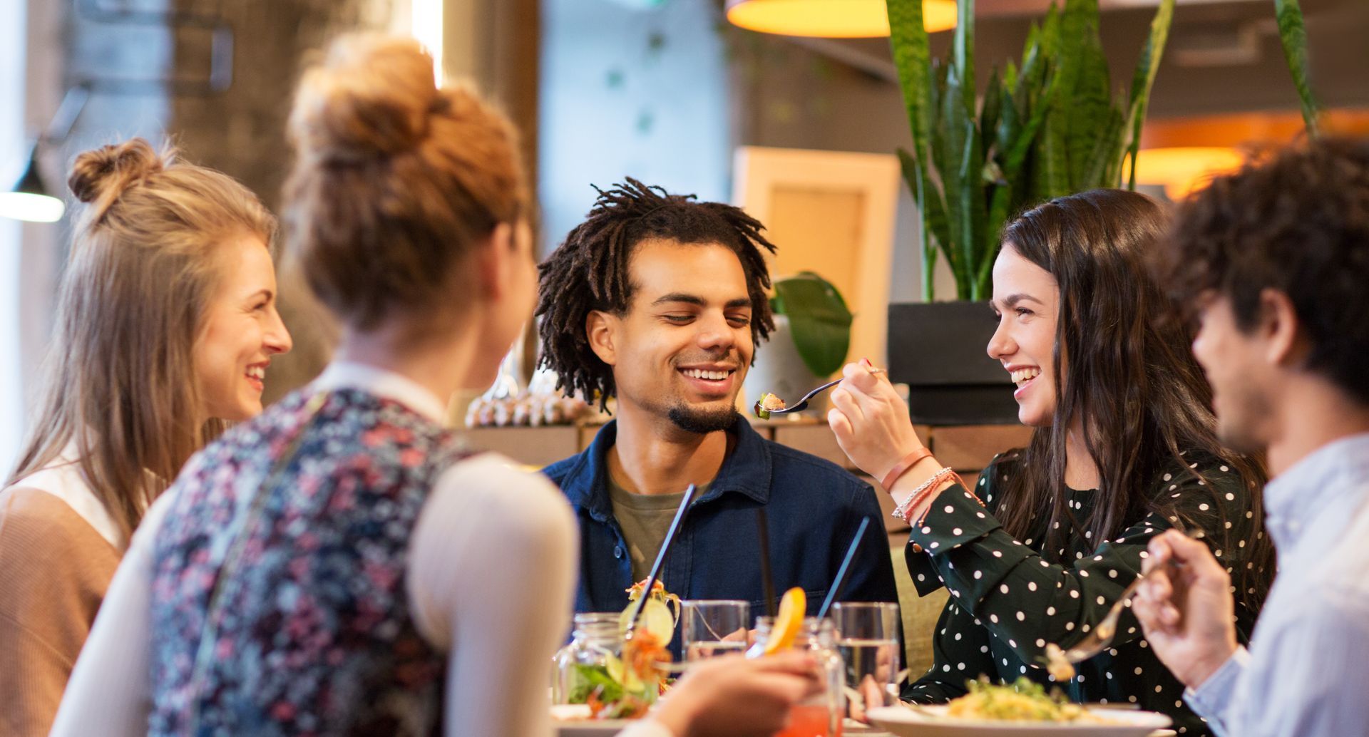 A group of people are sitting at a table in a restaurant eating food and drinking.