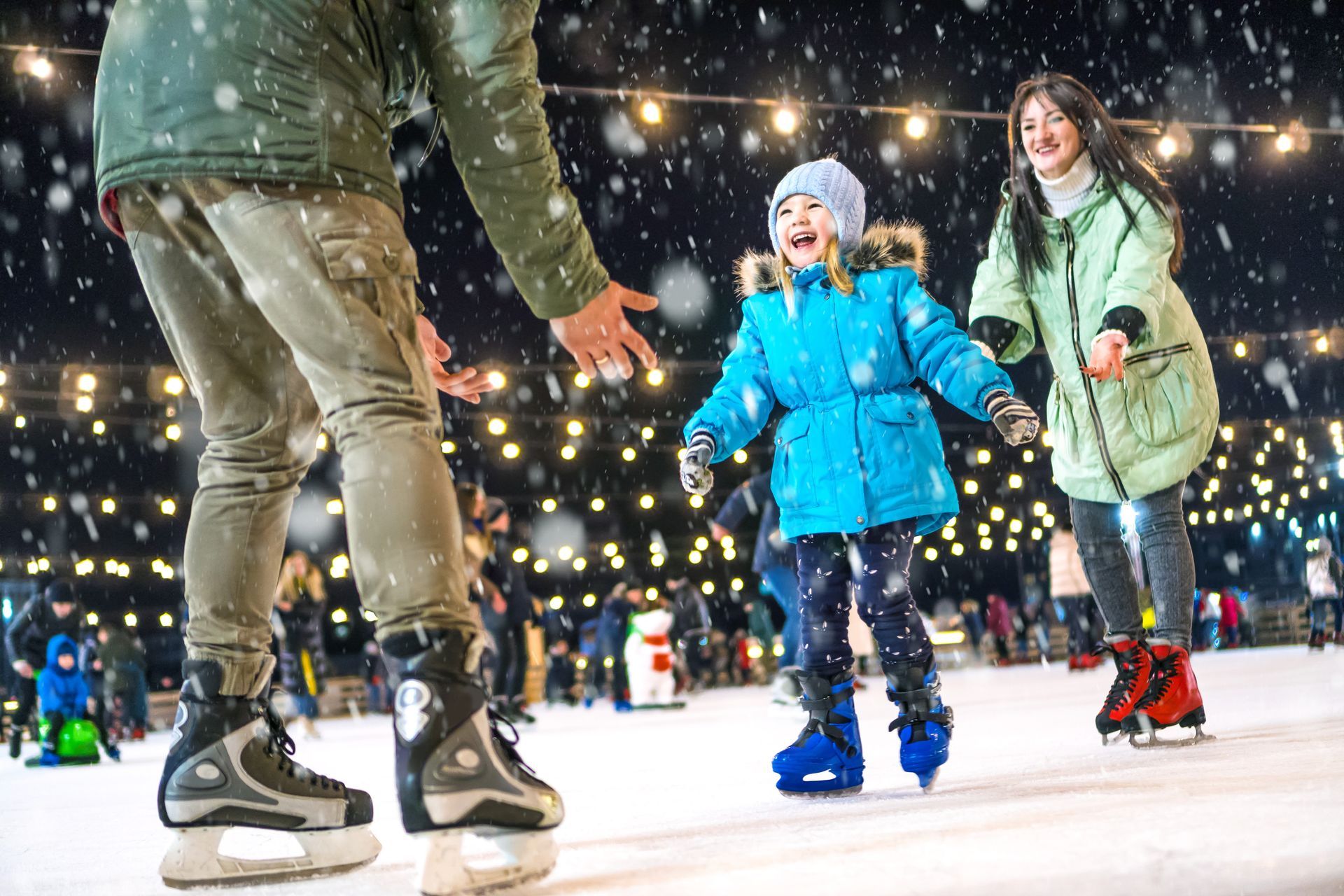 A family is ice skating on a rink at night.