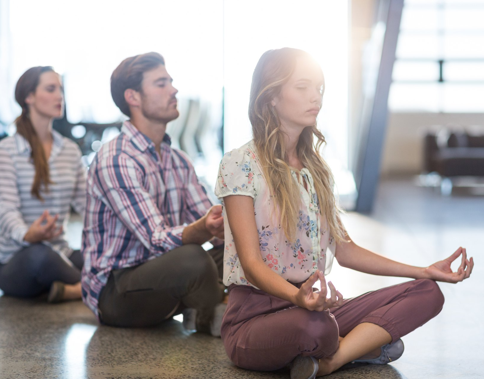 A group of corporate office people sitting on the floor meditating as they try to enhance their mood and wellbeing.