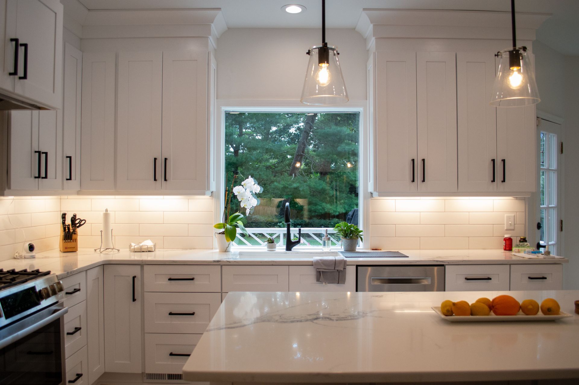 A kitchen with white cabinets , stainless steel appliances , and a large island.