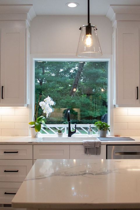 A kitchen with white cabinets , stainless steel appliances , and a large island.