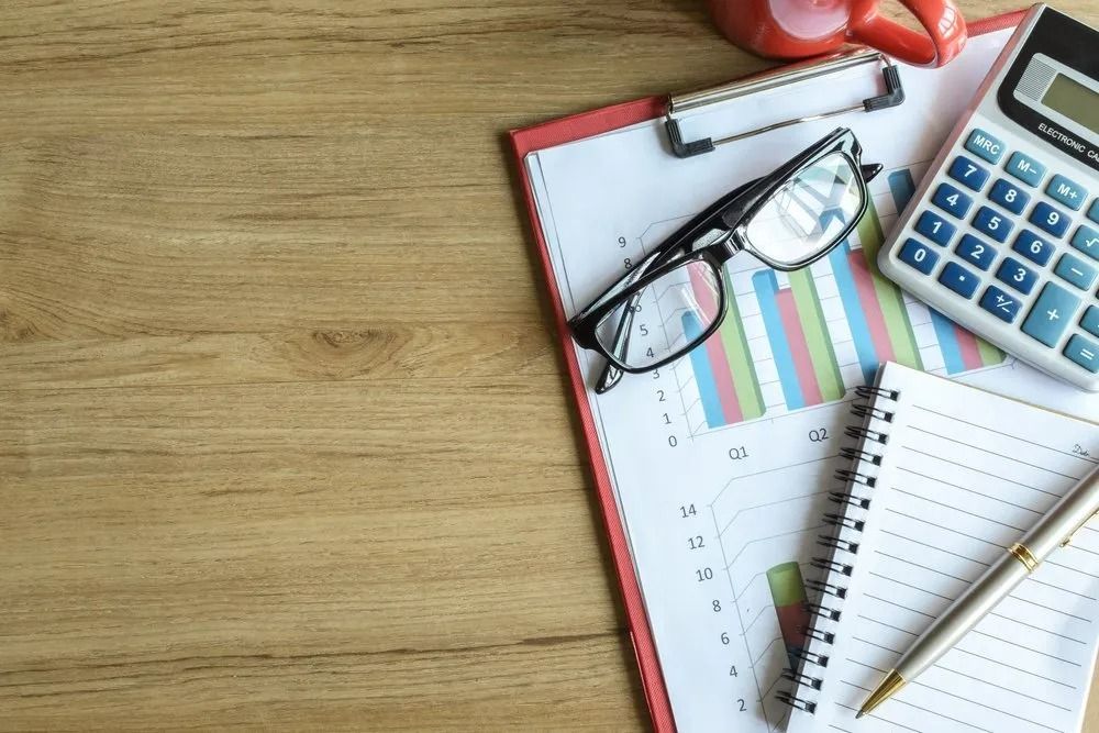 Clipboard with Charts, Glasses, Calculator, Notebook, Pen on Desk — All Finanz & Insurance Solutions Mackay in Cannovale, QLD