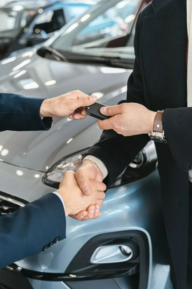Person Handing Car Keys and Shaking Hands in Front of Blue Car — All Finanz & Insurance Solutions Mackay in North Mackay, QLD
