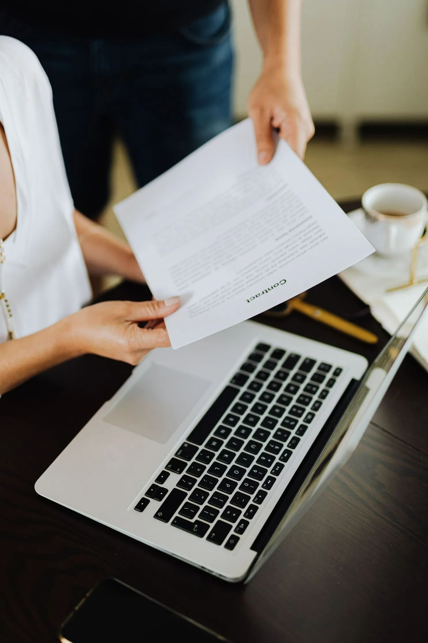 Person Handing Document to Another at Laptop — All Finanz & Insurance Solutions Mackay in Airlie Beach, QLD