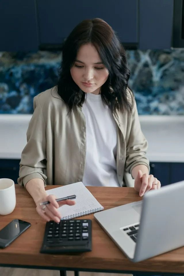 Woman Working With Financial Records at a Table — All Finanz & Insurance Solutions Mackay in North Mackay, QLD