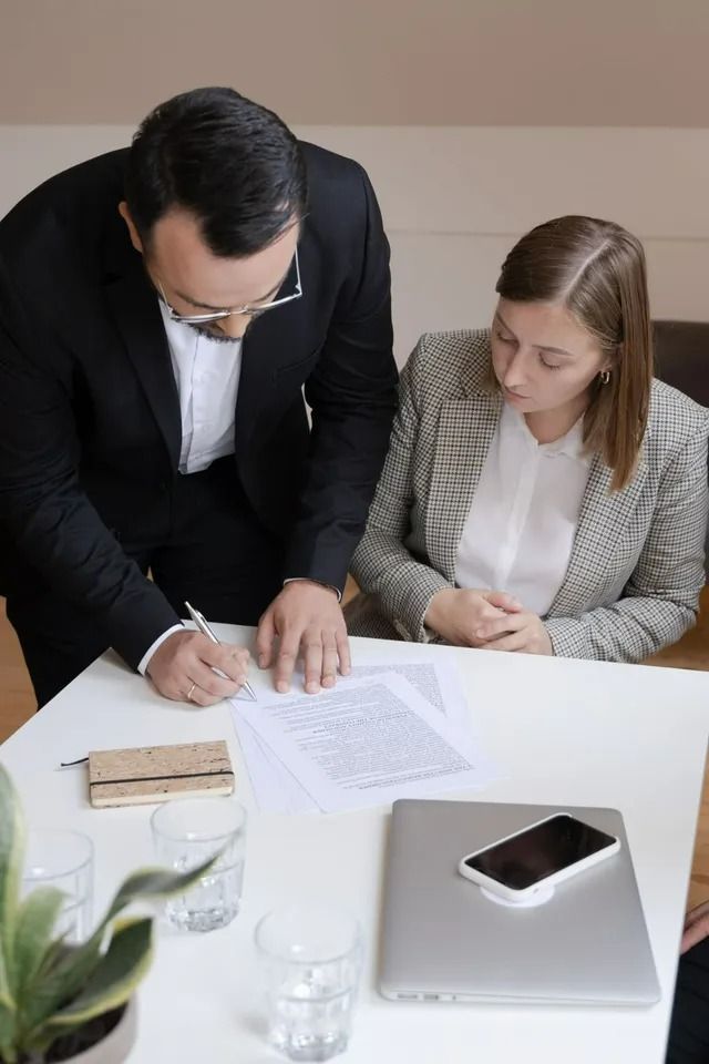 Man in Suit Signing Documents with Woman at Table — All Finanz & Insurance Solutions Mackay in Cannovale, QLD
