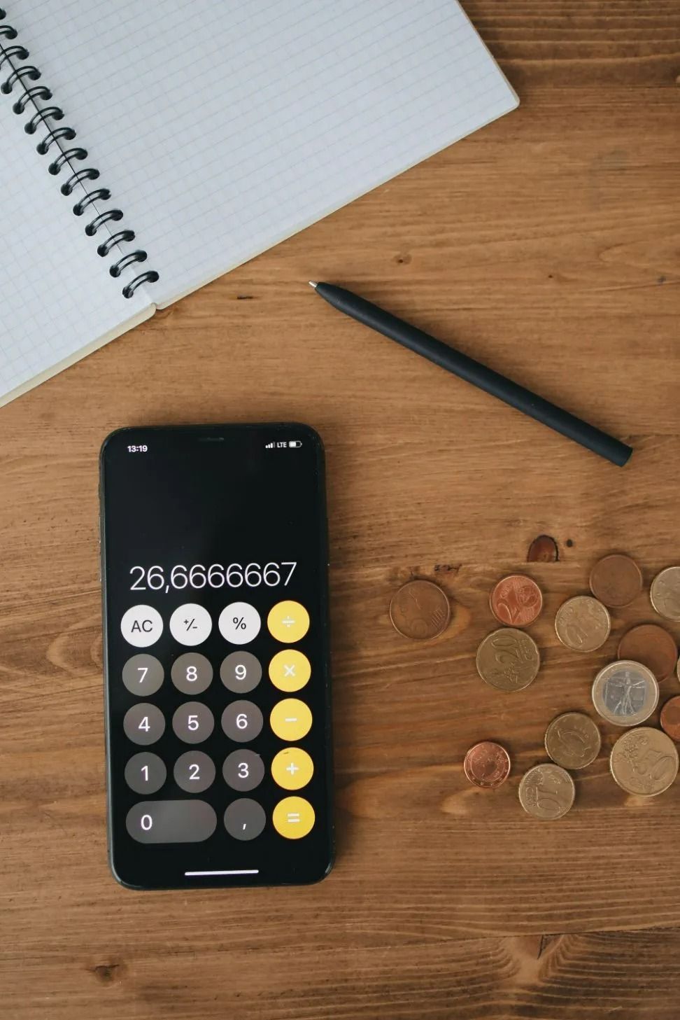Calculator App on Smartphone with Notebook, Pen, and Coins on Table — All Finanz & Insurance Solutions Mackay in Bowen, QLD